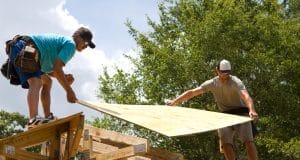 Construir con madera Carpinteros colocando tableros contrachapados en tejado de una casa