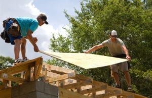Construir con madera Carpinteros colocando tableros contrachapados en tejado de una casa