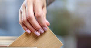Roble o pino, qué madera conviene para cada uso en casa Mano eligiendo una muestra de madera en un muestrario de especies