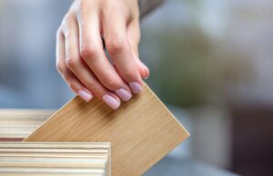 Roble o pino, qué madera conviene para cada uso en casa Mano eligiendo una muestra de madera en un muestrario de especies